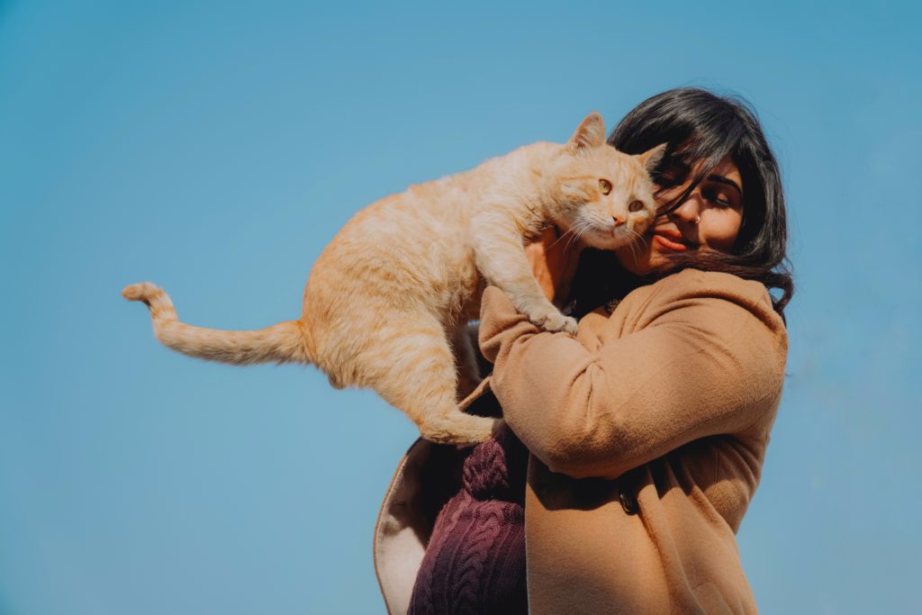 Happy woman with cat on blue sky background